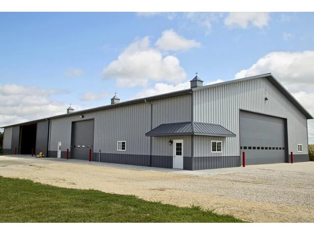 Large gray pole barn with overhead machinery doors built for a Minnesota farm operation
